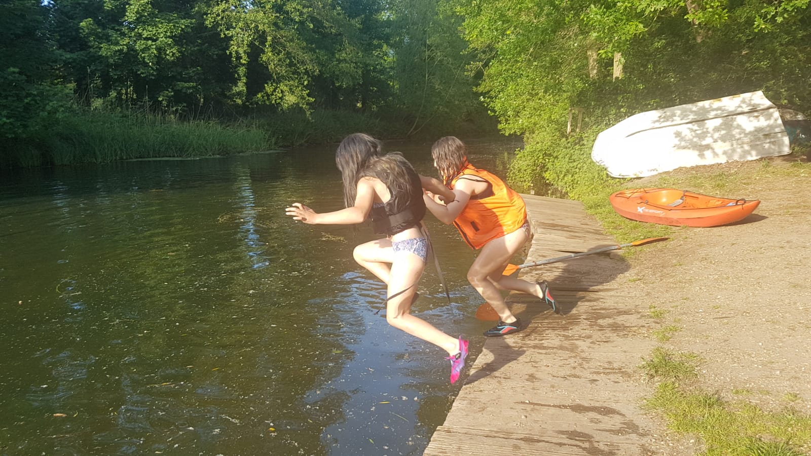 Children jumping into the river with lifejackets on